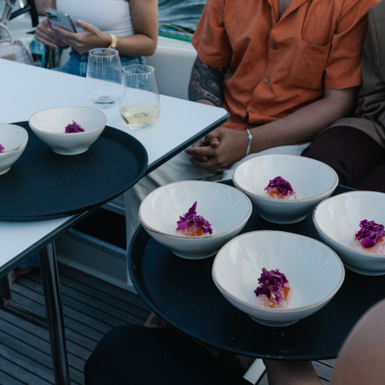 Small pink looking dishes in bowls and group of people waiting for food
