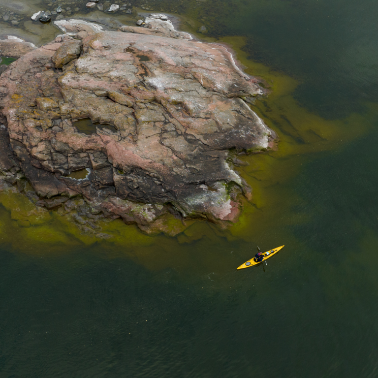 Person kayaking close to rocky island in Baltic sea