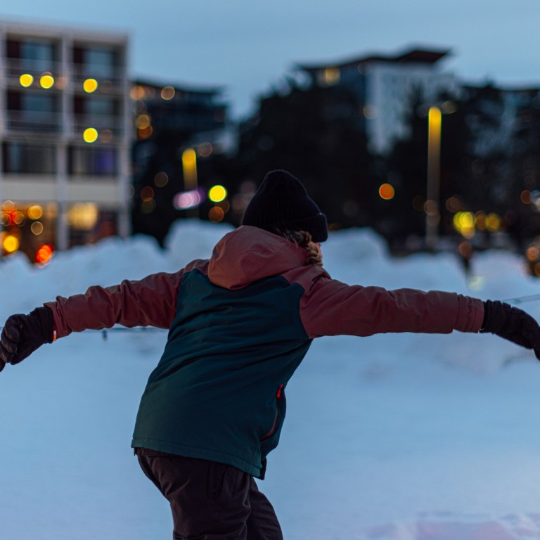 Lapsi takaapäin kuvattuna talvisessa Tapiolan jääpuutarhassa luistelemassa.