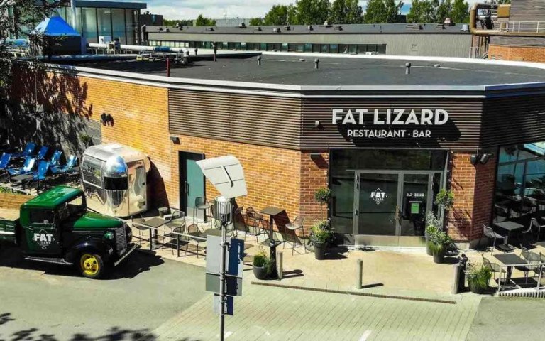 The façade and terrace of the Fat Lizard restaurant, with a pickup truck with the Fat Lizard logo in front of it.
