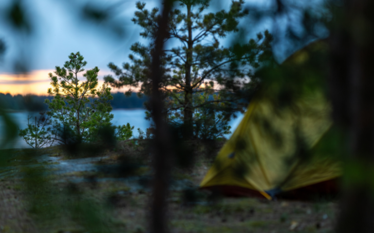 Blurred yellow camping tent and view to sunset on the island