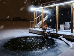 Woman dipping into ice cold water in front of Laguuni floating sauna