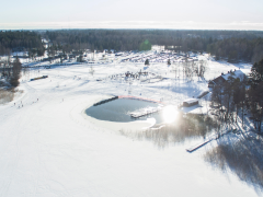 Dron view over Oittaa Recreational area covered in snow and people enjoying winter activities such as cross-country skiing